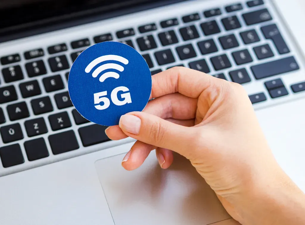 kobieta trzyma w ręce naklejkę z informacja o 5G